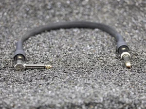 Custom-made Bangee audio patch cable 6.35 mm jack, black braided, angled and straight connectors with copper tips, grey background