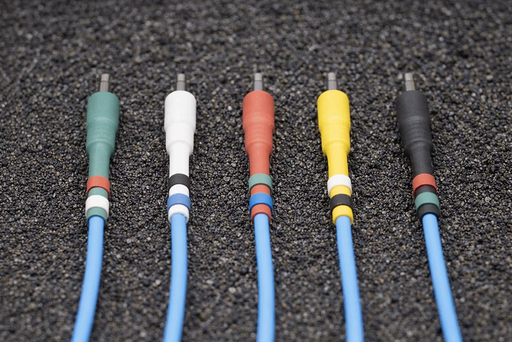 Blue Europatch Bangee patch cables with coloured sheaths for Eurorack synthesizers, grey background.
