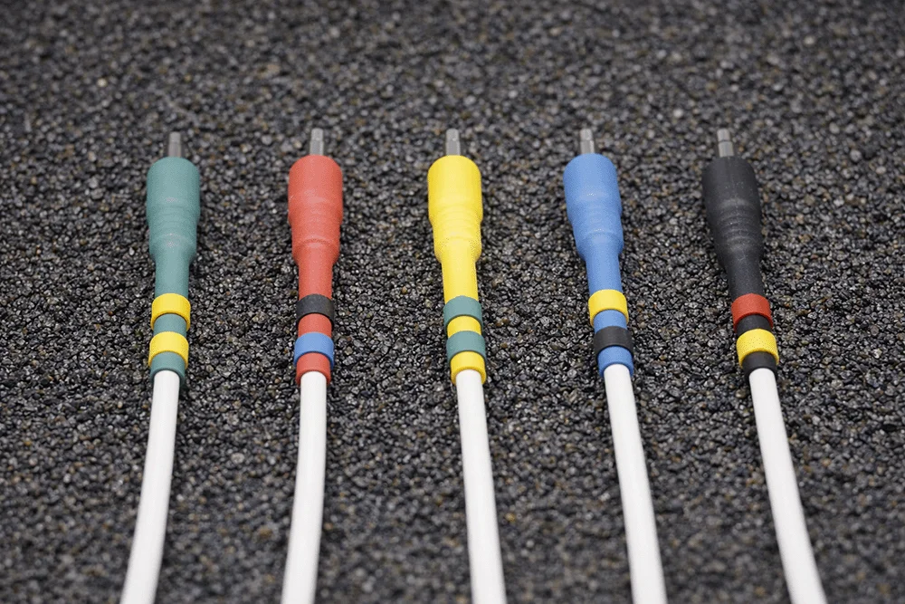 White Europatch Bangee patch cables with coloured sheaths for Eurorack synthesizers, grey background.
