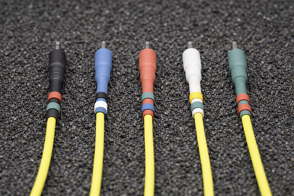 Yellow Europatch Bangee patch cables with coloured sheaths for Eurorack synthesizers, grey background.